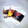 3 cards fanned out with colorful Adirondack art: left to right 9 of clubs natural stone bridge; 2 of hearts yellow and red leaves; joker Saranac Lake Ice Palace with fireworks bursting atop