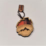 Single Adirondack Park-shaped wood/fabric ornament on a white background. Red plaid fabric shows through the top half with ADIRONDACK etched above the the image of mountain peaks etched in the bottom center.