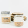 Left to right: one closed candle jar with manufacturer's label in center. Open candle jar in front of birch bark.