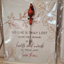 Single Cardinal pin with bird upright facing front on an illustrated card with the words NO ONE IS TRULY LOST WHEN THEY REMAIN IN THE HEARTS AND MINDS OF THOSE WHO LOVE THEM printed in bottom center. All seen through plastic packaging.