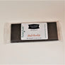Dark chocolate bar in clear wrapping with the white label in center: The Village Mercantile. Barkeater Chocolates in green type on left side.