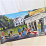 The print of the iconic ice cream stand, Donnelly's, on an open beach towel. White stand and house behind with people in solid colors ordering and eating.