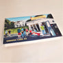 Flat image of the print of the iconic ice cream stand, Donnelly's, as the cover of a greeting card. White stand and house behind with people in solid colors ordering and eating.