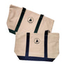 Two Eagle Island Camp Totes both off-white canvas with different colored accents. Top tote has green straps on both sides of the centered green Eagle Island Camp logo. The tote below has navy blue straps and logo.