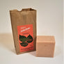 Small brown bag standing upright with SallyeAnder red poison ivy soap label next to a square beige bar of soap standing by its side.