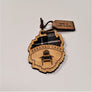 Single Adirondack Park-shaped wood/fabric ornament on a white background. Black plaid fabric shows through the top half with SARANAC LAKE etched above the image of an Adirondack chair in the bottom center.