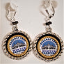 Dangling Winter Carnival circular earrings. Gold braided bands and black band surround Saranac Lake Winter Carnival blue, white & black logo.