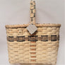 Woven wine basket in neutral color with olive and taupe accent trim trim in top third of basket and olive trim mixed in with handle above the basket.