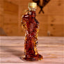 Glass maple syrup bottle filled with syrup and shaped like a hockey player with a gold-colored screw top sits on a wooden-slatted table.