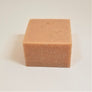 Square bar of poison ivy soap close up--beige soap with texture specs showing on top and front side.