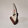 Ski tip clock in profile. Wooden base. Black and silver side with black battery area protruding from the back of the clockface.
