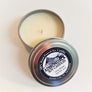 close up of cozy home candle open with top tin lid  leaning on the top of the candle