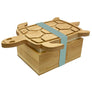 The turtle tofu press out of the box on a white background. The bottom is a rectangular wood block with an opening where a block of tofu is peaking through between the box bottom and the wood turtle lid. A light blue band holds it all together.