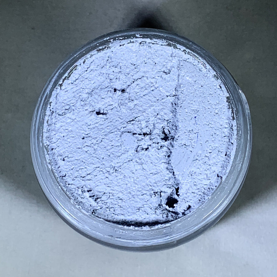 Inside of the jar of Niawen skin cream. A pale gray textured cream is shown with the lid off the jar.