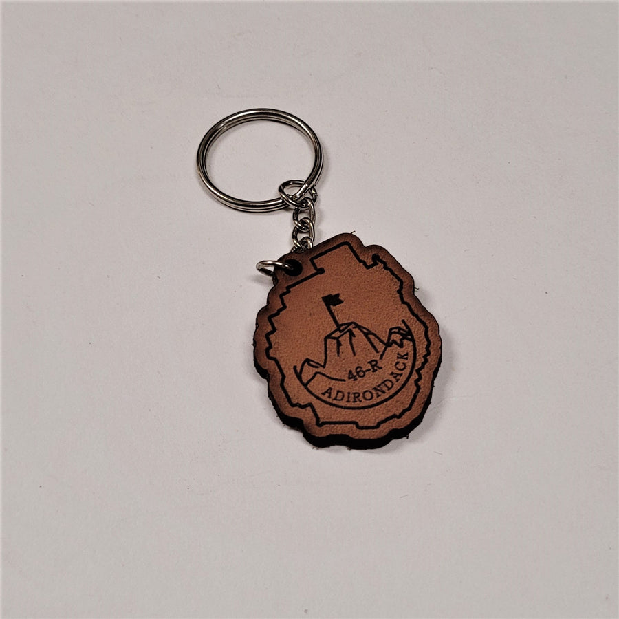 Single leather key chain with 46-R ADIRONDACK in brown lettering  curved below a mountain top with a flag planted in the center, all within the park outline, attached to a silver chain and keyring.