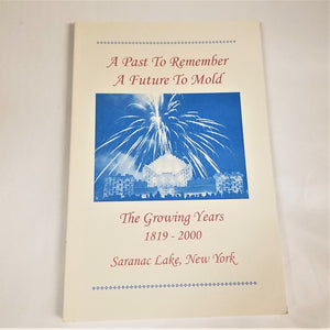 Cover of the  book A Past to Remember A Future to Mold. Red type set on a white background with a blue and white photo in the center of an Ice Palace with fireworks above it.
