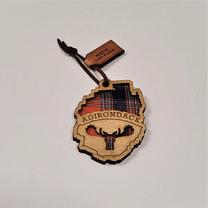Single Adirondack Park-shaped wood/fabric ornament on a white background.  Red plaid fabric shows through the top half with ADIRONDACK etched above the image of a plaid moose head showing through the bottom center.