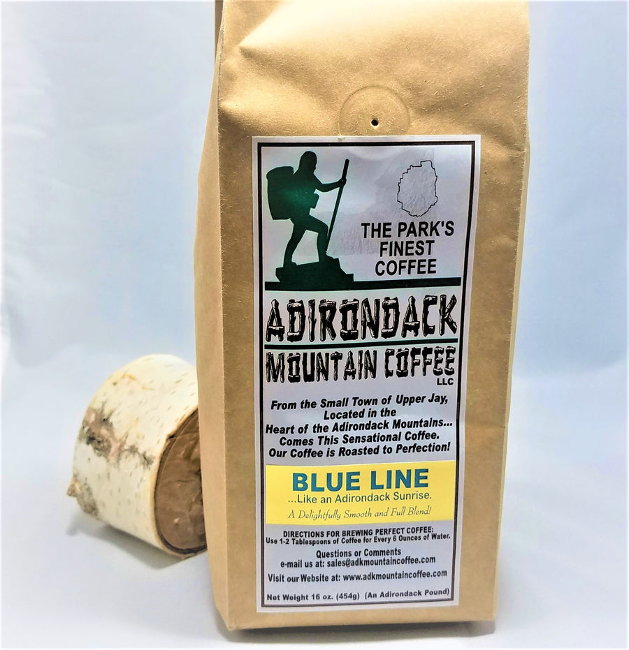 A package of Blue Line Coffee from Adirondack Mountain Coffee standing upright in front of a slice of birch wood.