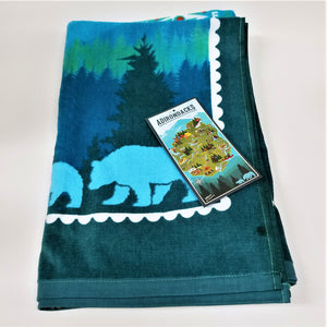 Folded portion of terry cloth towel depicting blue bears on a dark blue/green background with the manufacturer's promo tag on top
