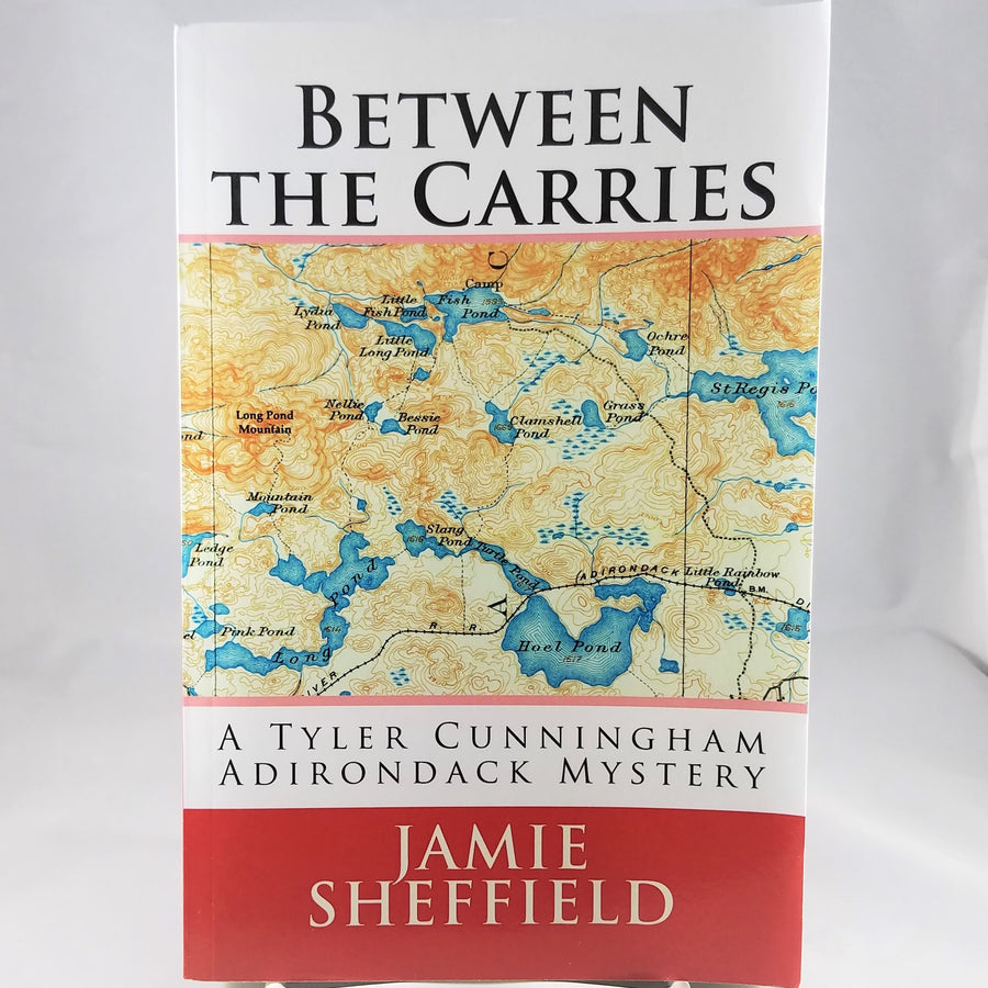 Cover of Between the Carries book by Jamie Sheffield with a map in the middle of  the book cover above the text: A Tyler Cunningham Adirondack Mystery