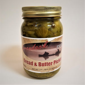 Glass jar of Bread & Butter Pickles with green pickles showing through around the label under a gold screw top.