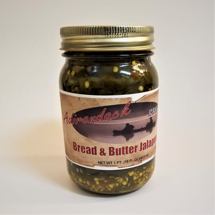 Glass jar of Bread & Butter Jalapeno Peppers with lots of jalapeno seeds showing through the jar around the label under the gold screw top.