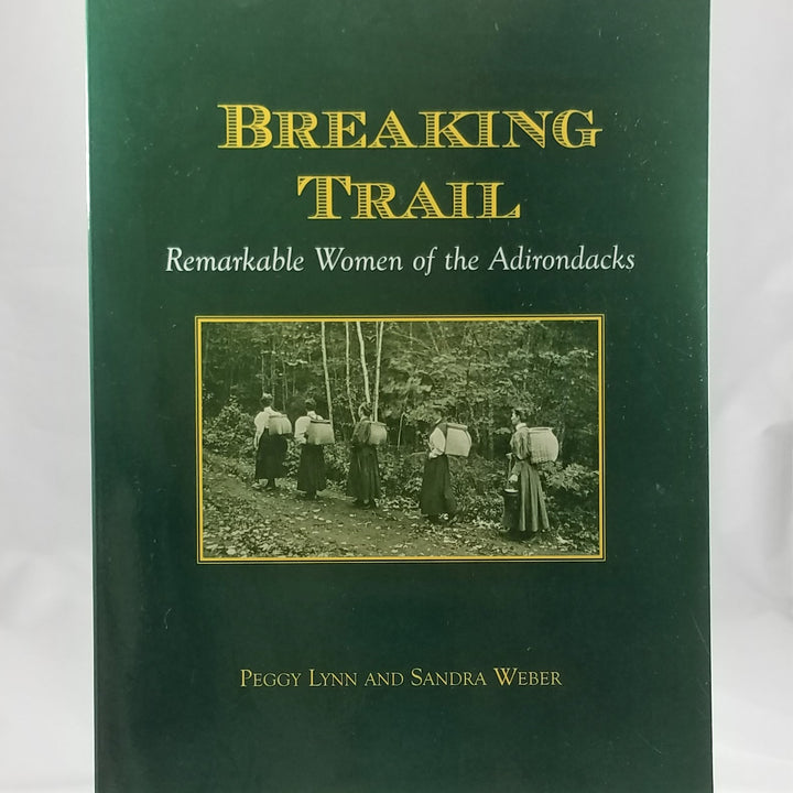 Green book cover of Breaking Trail with vintage photo in center of period women hiking with their packbaskets on their backs
