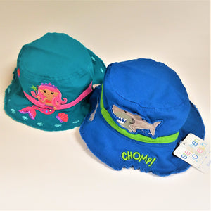 Two toddler-sized bucket hats. Left qua with a pink mermaid and pink band. Right , bright blue with a green band and work CHOMP! a grey shark above that and a bite taken out of the hat under the word CHOMP!