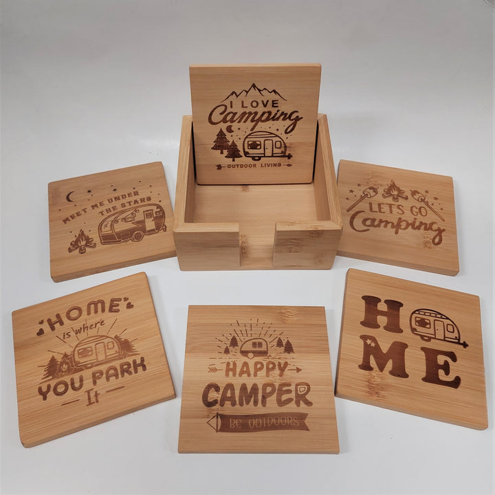 Five wood-looking square coasters surround the wood box with the sixth coaster inside it. Camp saings are letter into the wood along with classic camper images.