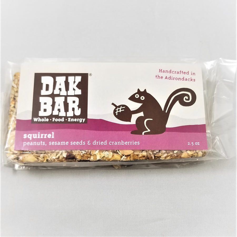 The front of the squirrel Dak bar with some actual bar peeking through the bottom and left side of the packaging. The squirrel dak bar has peanuts, sesame seeds & dried cranberries.