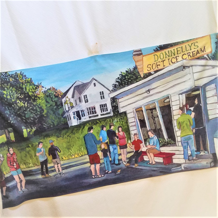 The print of the iconic ice cream stand, Donnelly's, on an open beach towel.  White stand and house behind with people in solid colors ordering and eating.