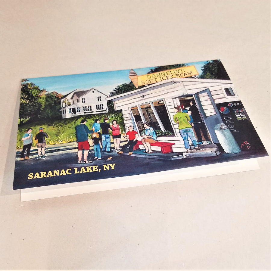 Flat image of the print of the iconic ice cream stand, Donnelly's, as the cover of a greeting card. White stand and house behind with people in solid colors ordering and eating.