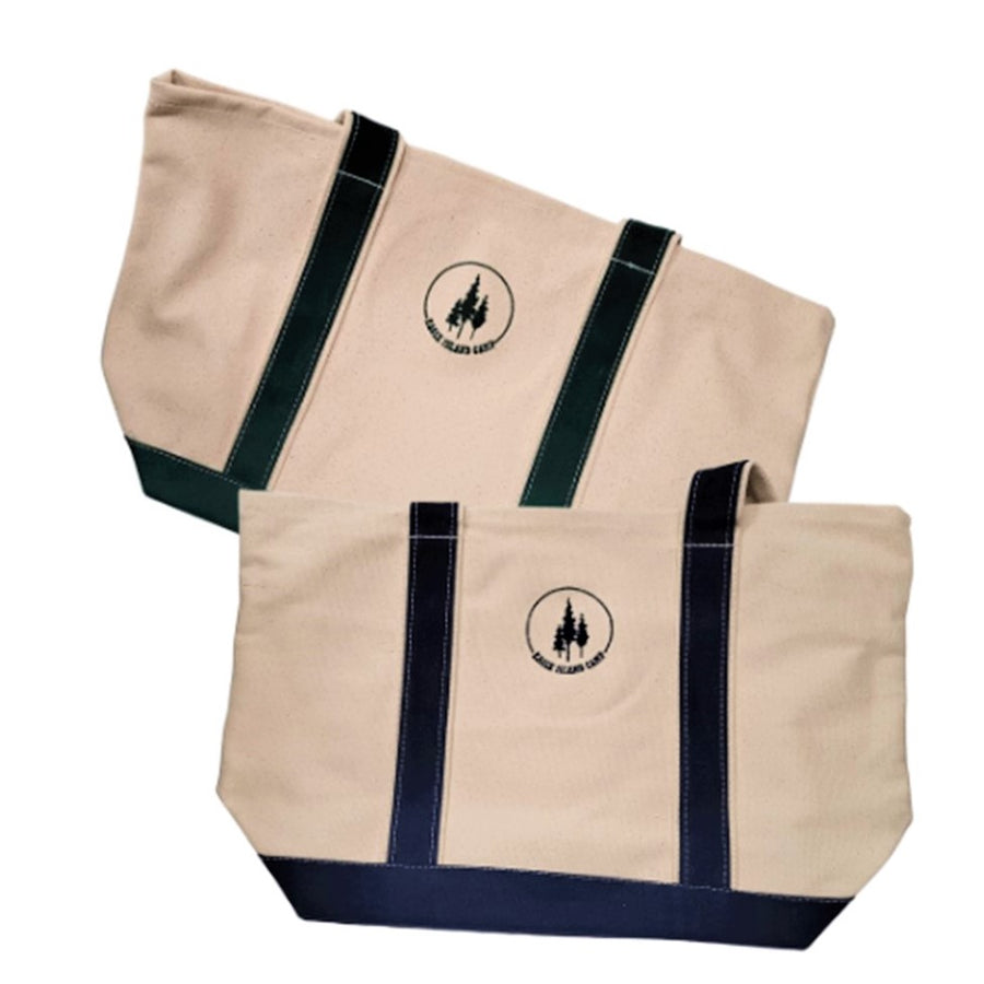 Two Eagle Island Camp Totes both  off-white canvas with different colored accents. Top tote has green straps on both sides of the centered green Eagle Island Camp logo.  The tote below has navy blue straps and logo.