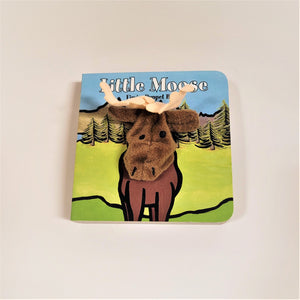 Little Moose finger puppet book with cloth head of bear coming out of the flat book cover. Moose is brown with black accents and cream-colored cloth antlers drawn into a green field with pine trees and mountains in the background.