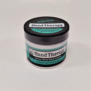 White round container with black twist lid. The labeling is green and black with a gray hand print to the left of the words Hand Therapy. 