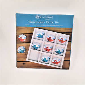 Box cover of Happy Camper Tic Tac Toe with white text in addition to the title: Willow Street Designs; Includes wood playing board, 5 red campers and 5 blue camper playing pieces. Then a picture of the campers in a white board with two campers outside the board, all on a wooden background.