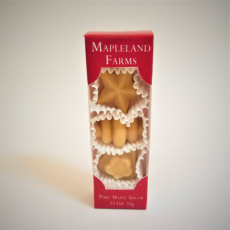 Three pieces of shaped pure maple sugar candy standing vertically in red-boxed packaging. The candies are in separate white crinkle paper cups.