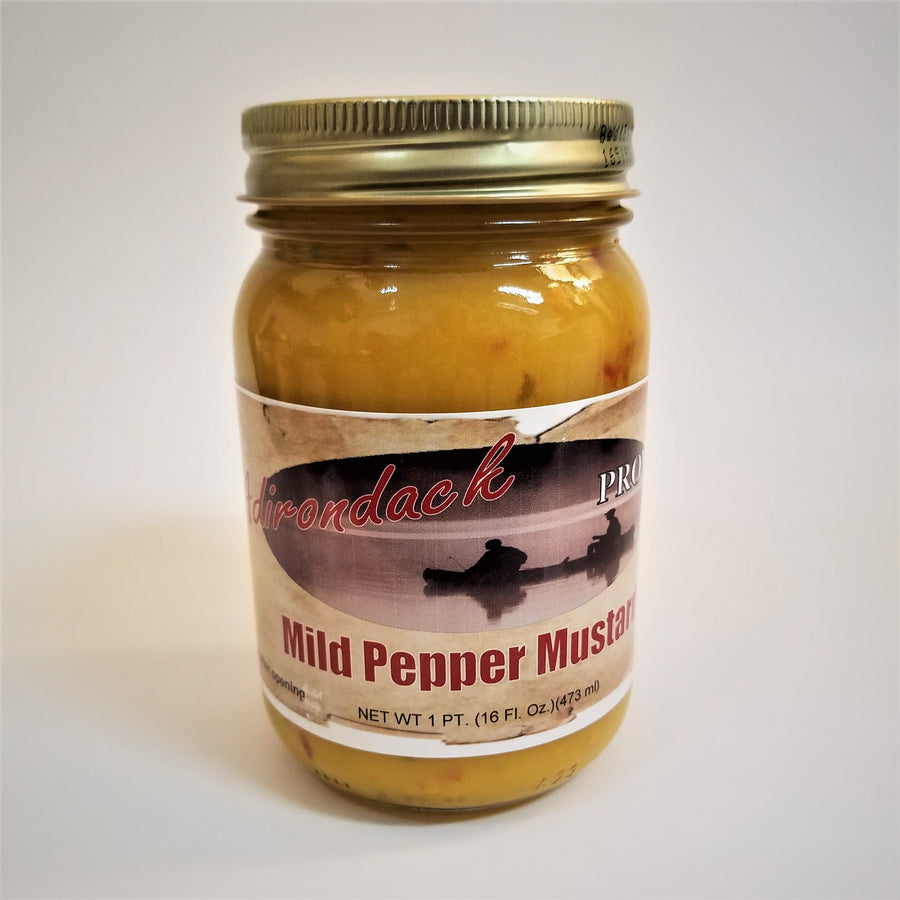 Clear jar of Mild Pepper Mustard with Adirondack Provisions label in the front center. Yellow mustard with a tinge of red pepper specks show through the clear jar above the label. Gold screw top.