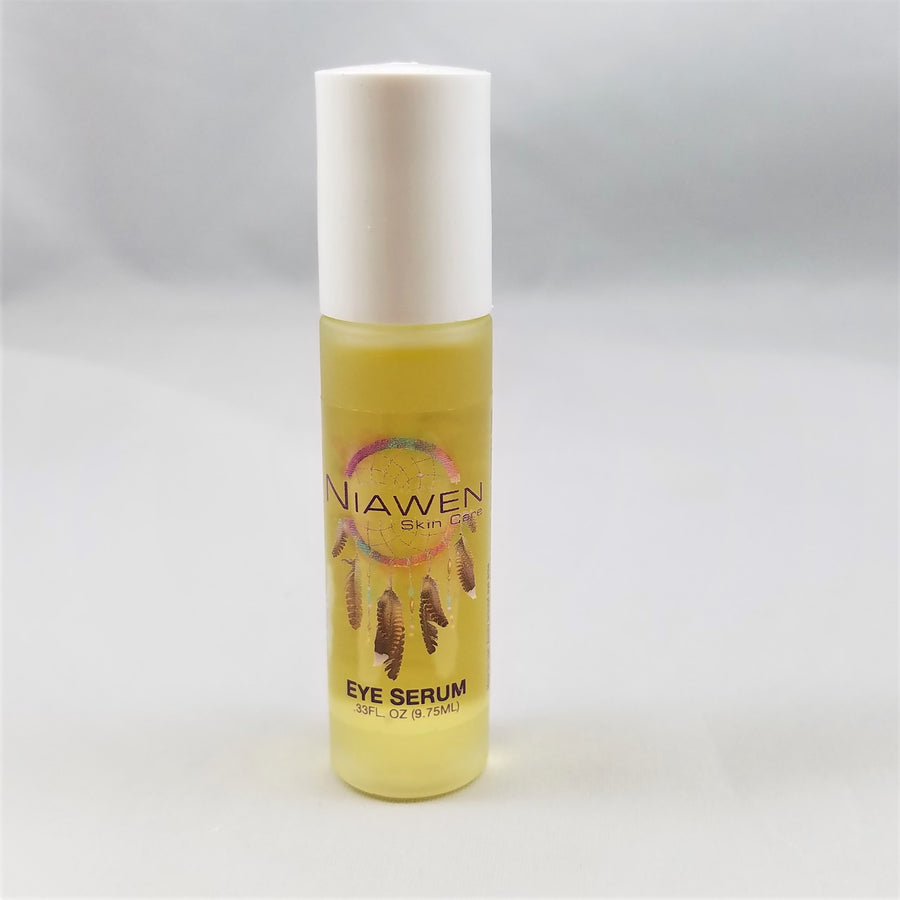 Standing vial of Niawen Eye Serum. White twist top with clear bottle bottom. Yellow serum shows through around the Niawen logo with colorful circle and gold feathers hanging below.