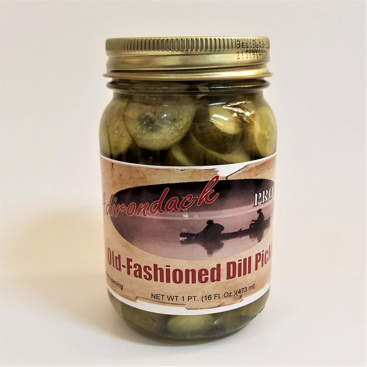 Glass jar of Old-Fashioned Dill Pickles with lots of sliced green pickles showing through the jar around the label under the gold screw top.