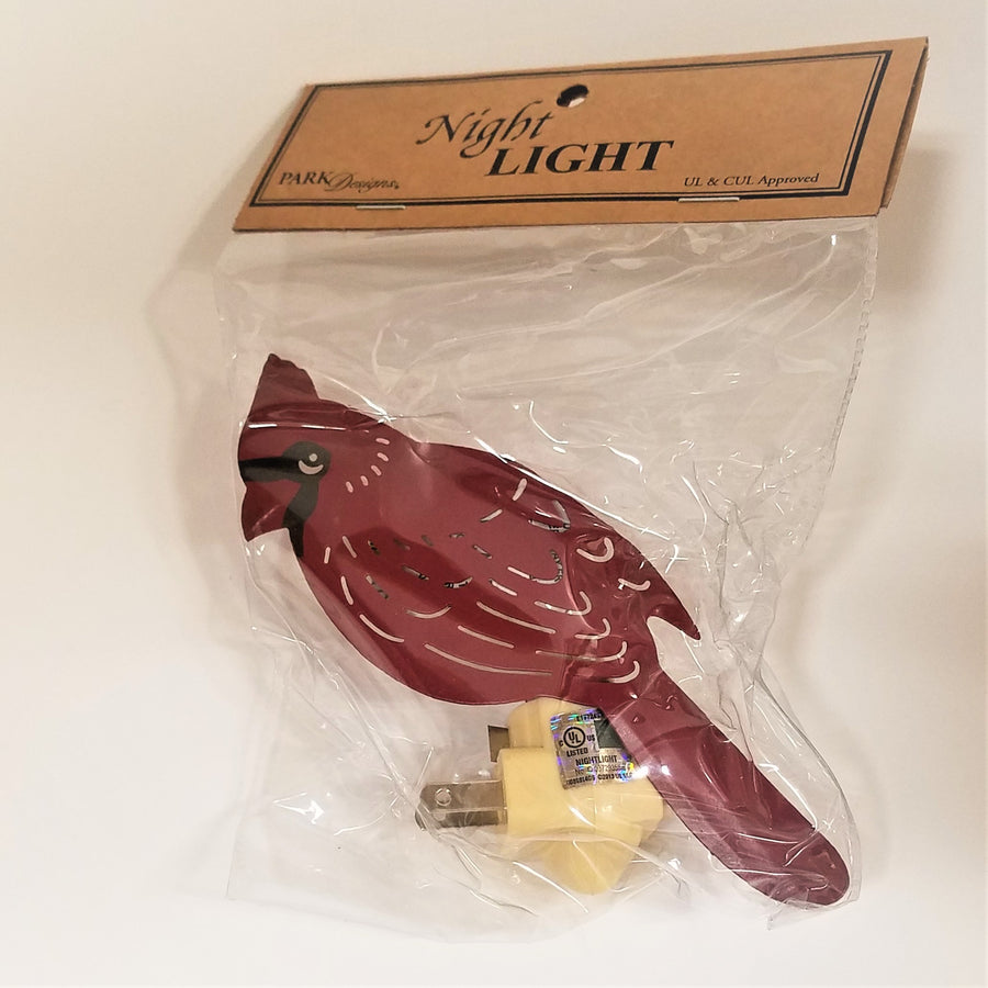 Red cardinal nightlight in its packaging. Brown label above a clear plastic bag showing the red bird and off-white plug socket below.