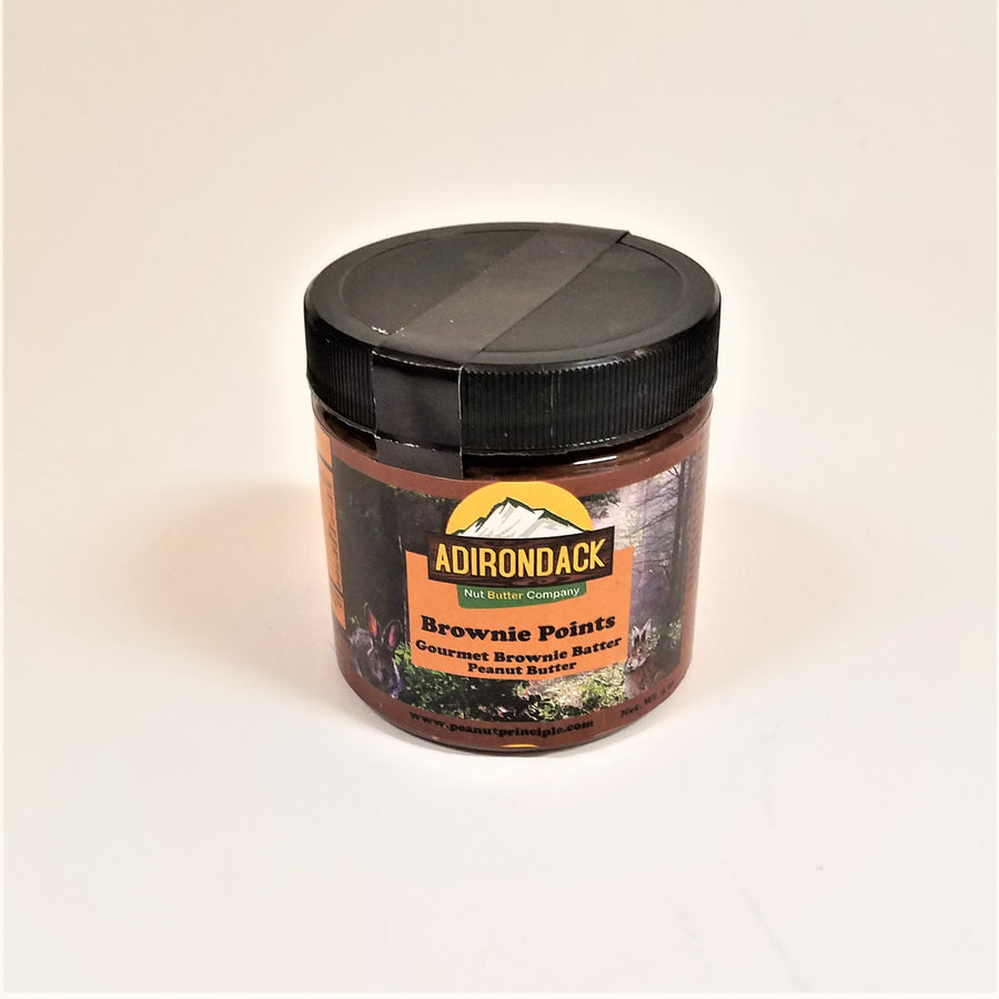 Brownie Points gourmet peanut butter in its plastic jar with a black screw lid. Rabbits and forest are featured on the label surrounding the type.