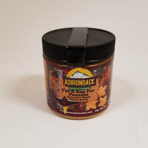 I'm a Sap for Peanuts gourmet peanut butter in its plastic jar with a black screw lid. Maple leaves and  autumn foliage are featured on the label surrounding the type.