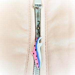Fish lure zipper pull attached to zipper. Fish points down and is pink, blue and white with black dots on the left in the pink and blue sections.