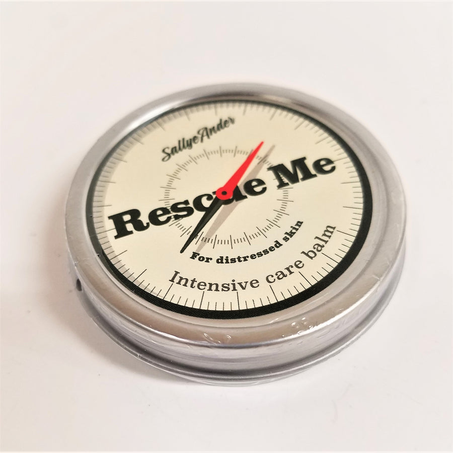 Single tin of Rescue Me sitting flat on a white surface. Silver circular tin with a compass-face look on the inner top circle. Black type on the label says SallyeAnder Rescue me For distressed skin Intensive care balm