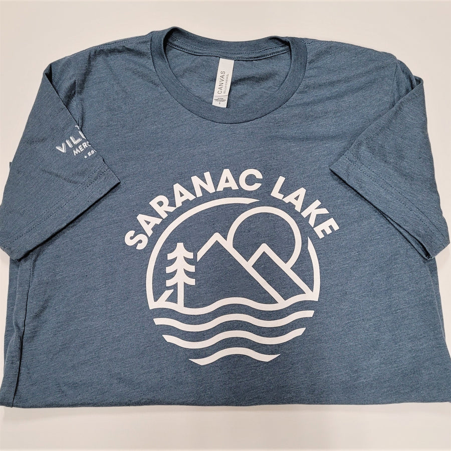 Folded gray-blue t-shirt. White lettering SARANAC LAKE arcs over a white logo of sun, mountains, evergreen and water. Short sleeves are turned in to reveal a vew white letters on the right sleeve. VIL MER