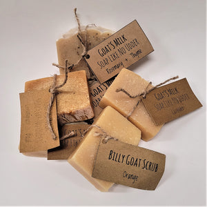 Grouping of 6 bars of Cook Farm Goat Milk soap on a white background. Beige soap labels are attached to each bar of soap with beige twine.