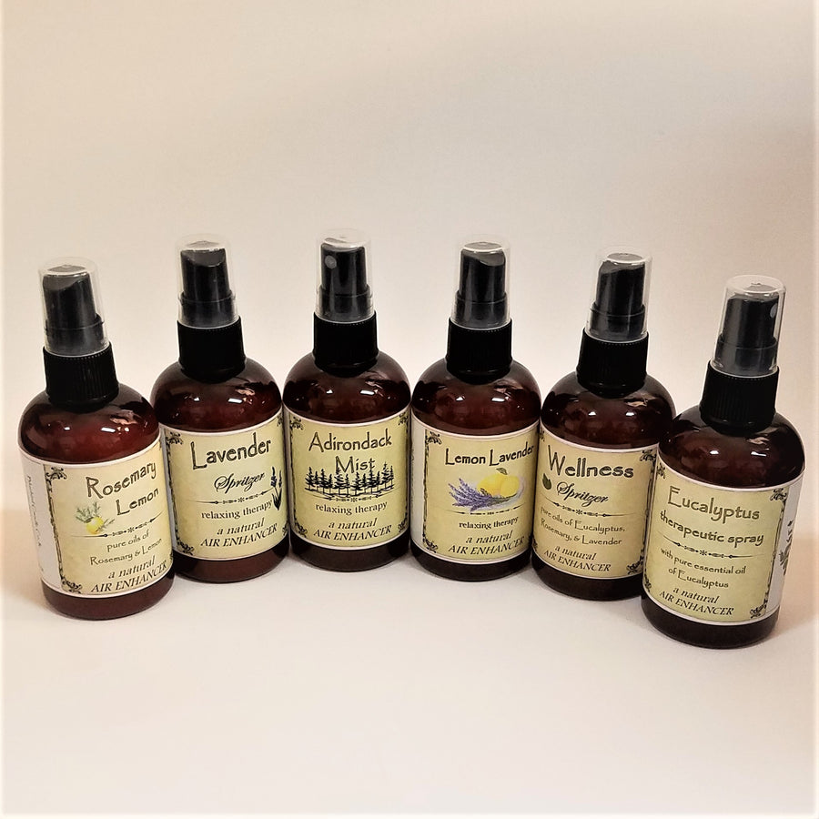 Six brown spray bottles of Spritzer with labels facing forward: Rosemary Lemon, Lavender, Adirondack Mist, Lemon Lavender, Wellness, Eucalyptus