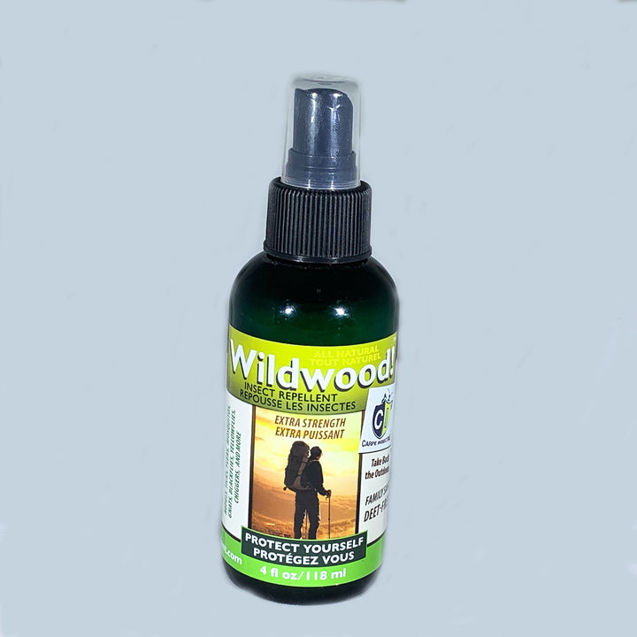A bottle of Wildwood bug repellent with green and white label under a black screw top with a spray nozzle under a clear cap.