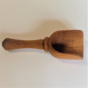 Wood grain scoop pictured lying flat with the scoop side on the right. Dark wood grain.